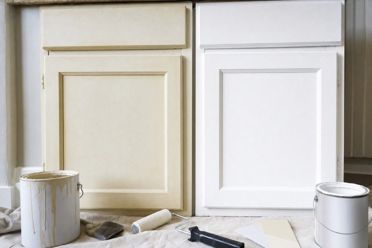 An aged yellowed white cabinet door next to a freshly repainted bright white one